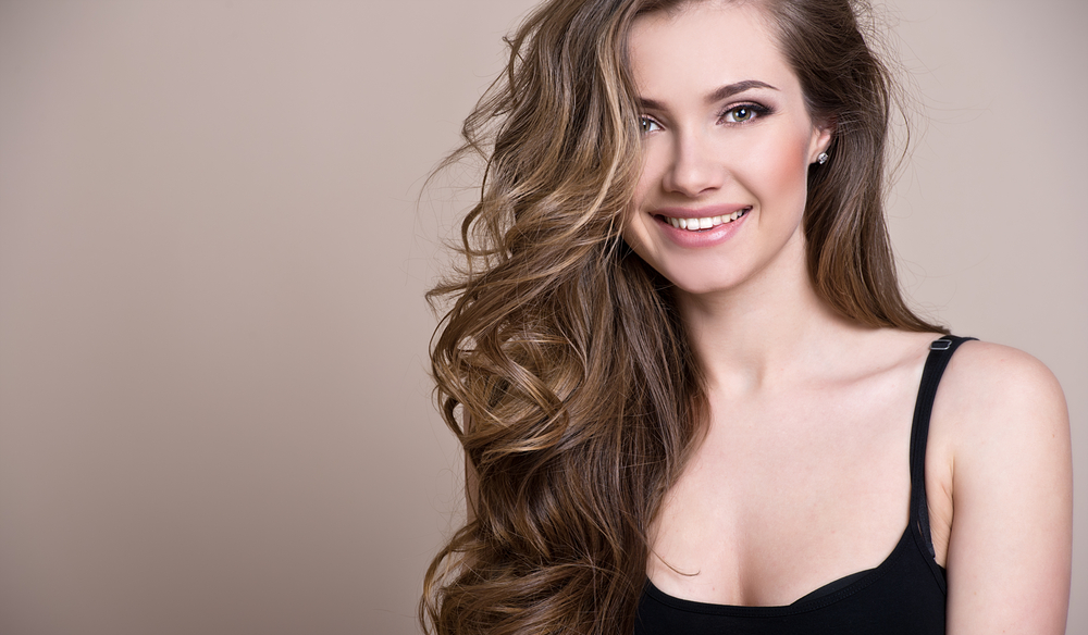 smiling woman with brown wavy hair wearing a  black top