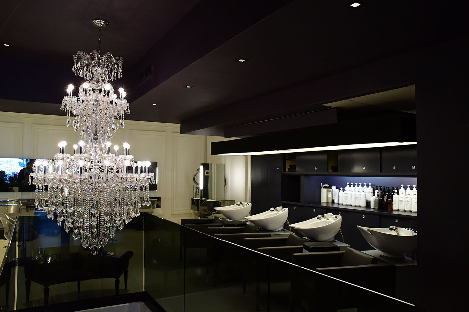 Dimly lit salon with chandelier and sinks
